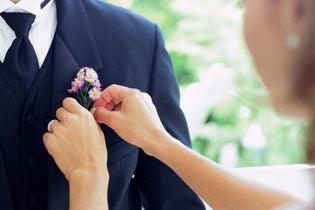 Girl using floral pins to pin boutonniere on boy