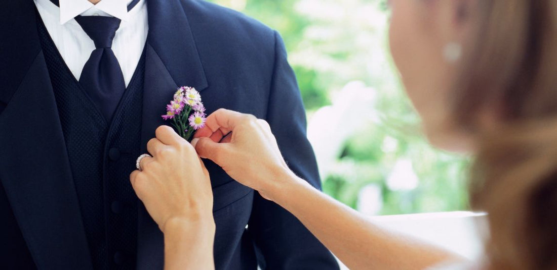 Girl using floral pins to pin boutonniere on boy