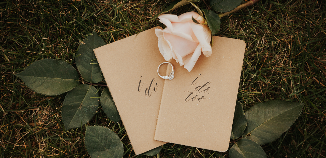 5 Reasons to Choose Roses single stem rose laying over wedding couple's vow books