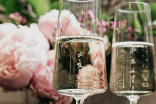 two glasses of champagne in front of big pink peonies