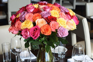 orange, pink, yellow, purple, and hot pink rose bouquet in the center of table
