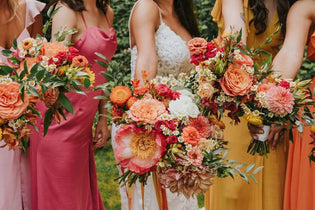 vibrant orange, pink, and yellow wedding flowers help by bridal party