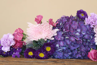 purple hydrangea and other purple flowers flay lay on a wooden table