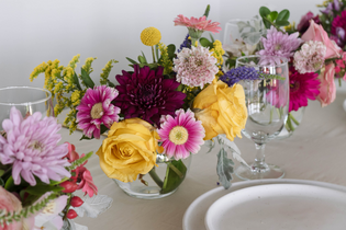 table centerpieces with pink, yellow, and purple flowers at dinner table