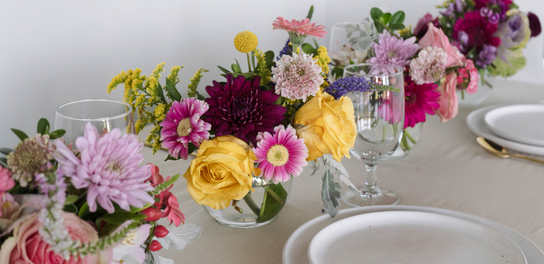 table centerpieces with pink, yellow, and purple flowers at dinner table