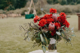 red carnation wedding bridal bouquet in clear vase outside