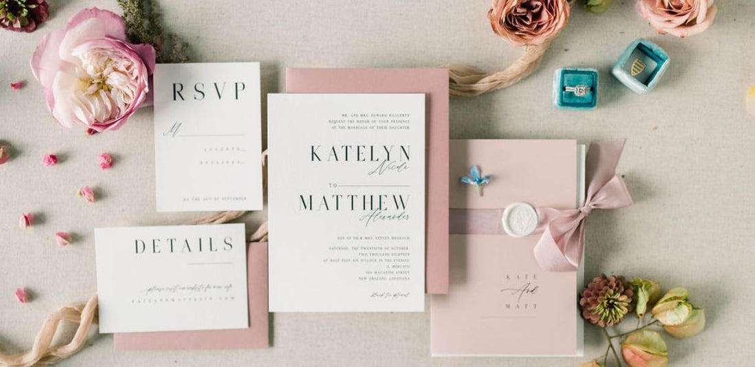 pink and white wedding invitation with a pink bow and pink flowers flat lay