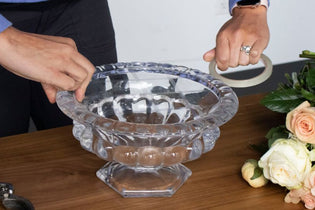 clear vase being taped with a grid for flower arranging and white, peach, and pink flowers on the table