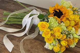 yellow bouquet on a wooden table wrapped in white ribbon