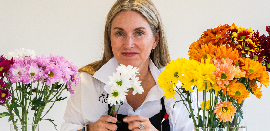 Liza Roeser holding white daisies and surrounded by pink, yellow, orange, and red daisies