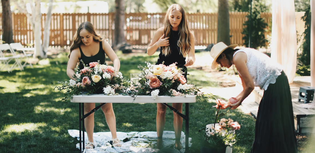 three women standing at a table customizing their table centerpieces