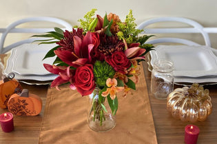 red and green and orange rustic table scape with fresh flowers in a mason jar