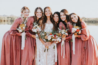 bride with her bridemaids in pink dresses while holding bouquets