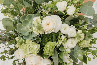 bridal bouquet with green and white flowers in it