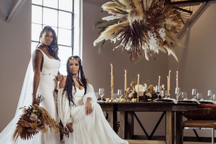 two brides at their boho wedding, one is standing and one is sitting