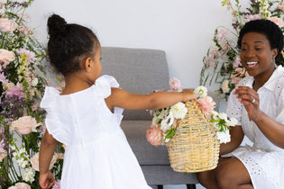 toddler giving her mom a basket full of pink and white flowers
