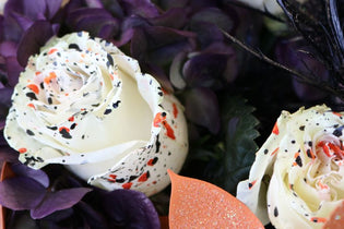 White roses with orange and lack splatter and black and orange flowers