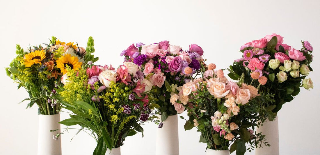 five mother's day bouquets in white vases