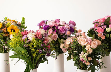 five mother's day bouquets in white vases
