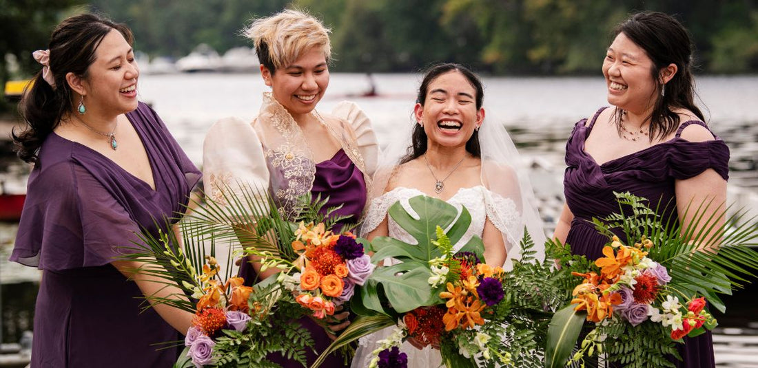 bride with her three bridesmaids in purple dresses with tropical flower arrangements