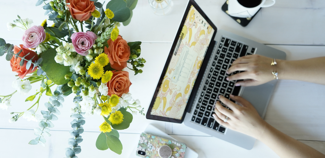 Laptop and flower arrangement on a wooden table