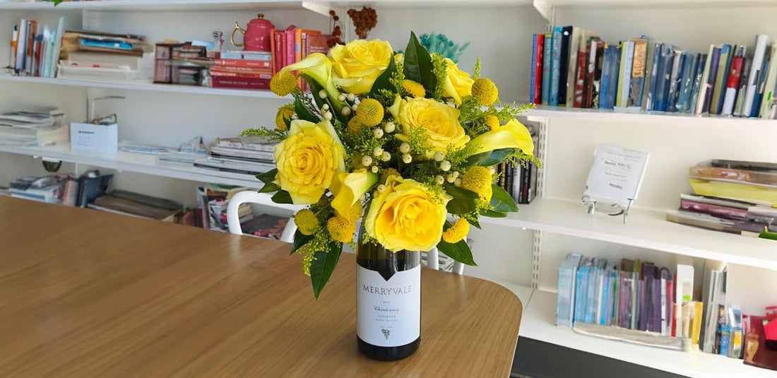 wine bottle with a yellow flower arrangement on top of it