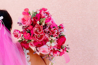 Bride with hot pink veil holding gummy pink bouquet over her right shoulder