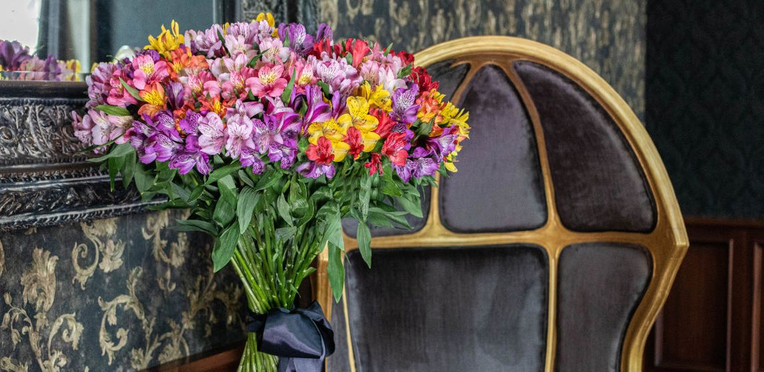 purple, yellow, and red alstroemerias in a vase on a table next to a black chair