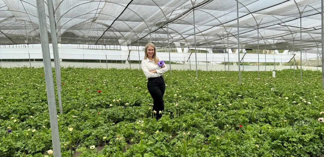 Liza Roeser standing in the middle of a flower field with her arms crossed and shes smiling