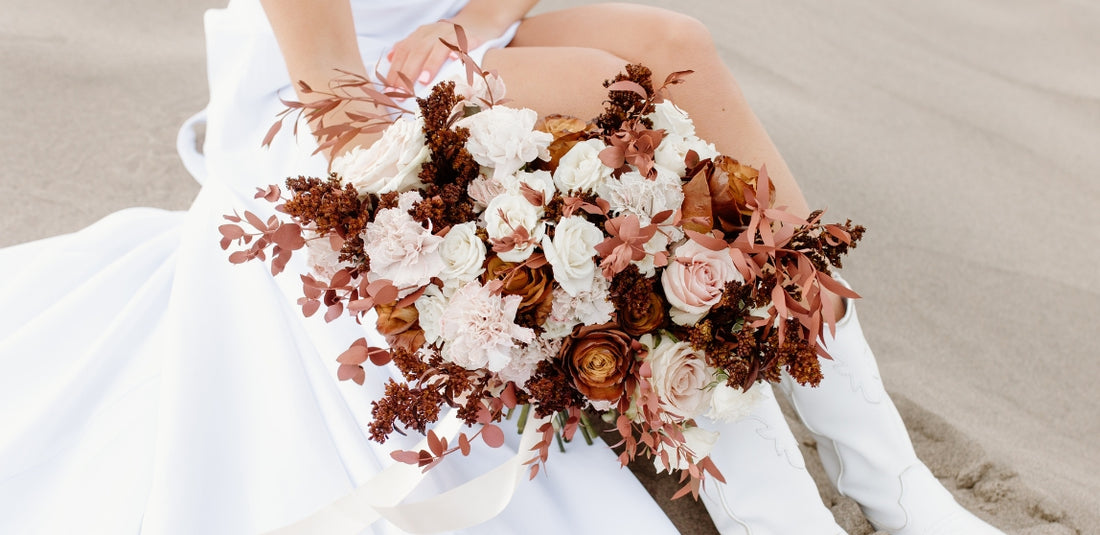 Mocha Brown Flowers Held In Hand By Bride Sitting In Sand