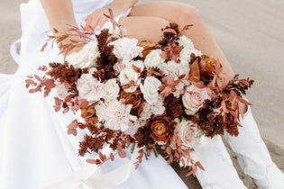 Mocha Brown Flowers Held In Hand By Bride Sitting In Sand