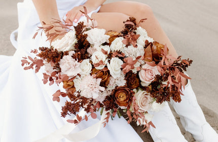 Mocha Brown Flowers Held In Hand By Bride Sitting In Sand