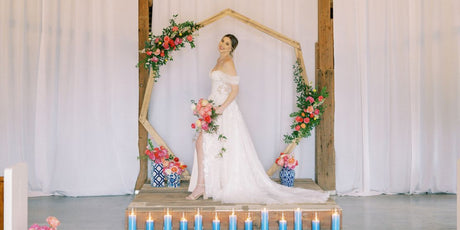 bride at alter with geometric arch with pink flowers and greenery