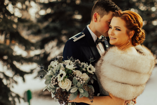 Winter Wedding Flowers in Every Color featured image wedding couple with white flower bouquet in the snowy trees